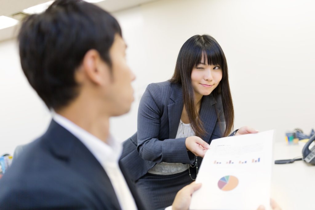ウィンクをして資料を渡す女性